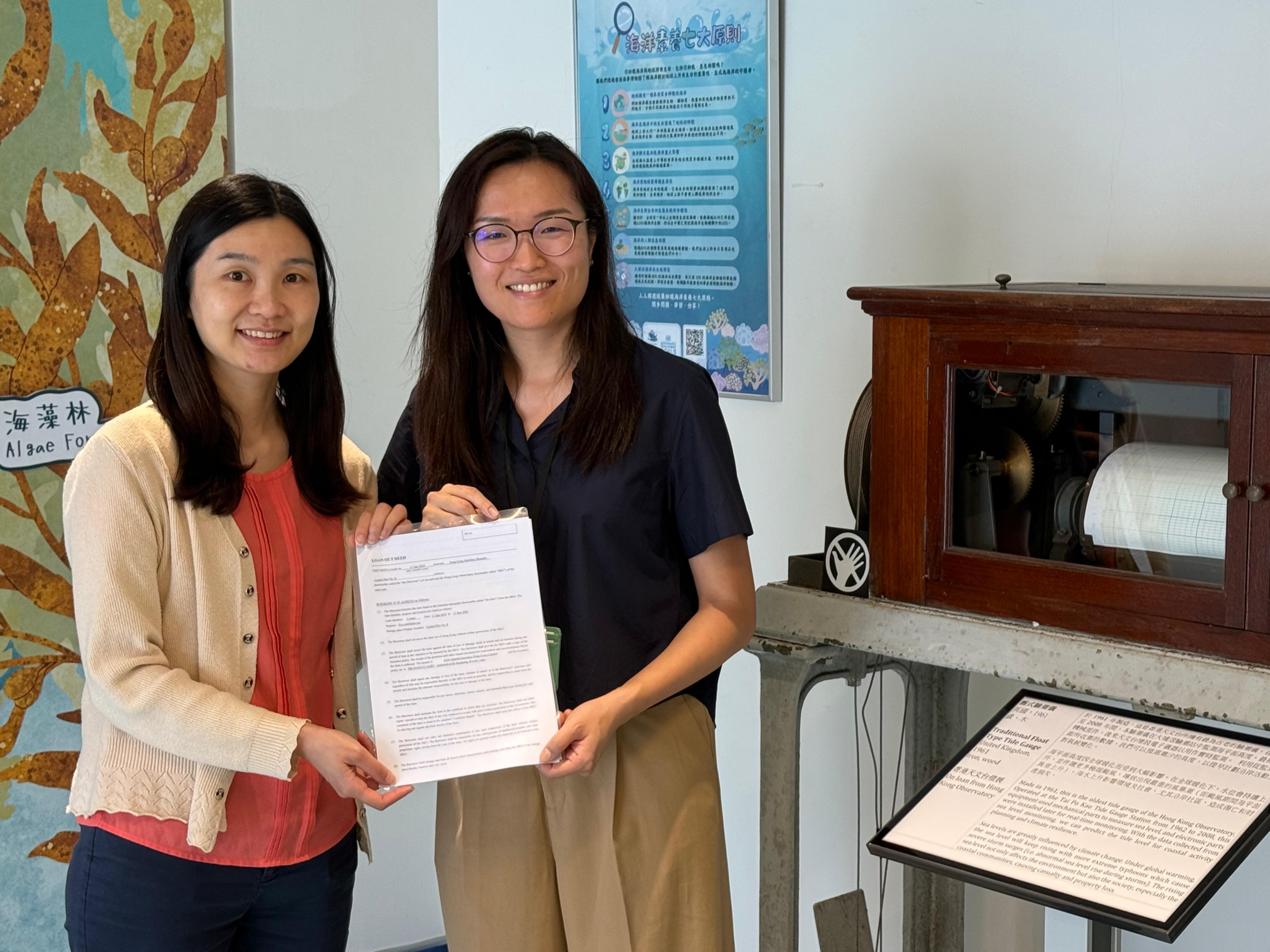 天文台科學主任李鳳瑩女士（左）向香港海事博物館海洋探知館主管伍家恩博士（右）移交驗潮儀借展協議書