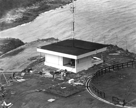圖三 : 在1983年9月，颱風愛倫正面吹襲下，赤鱲角臨時氣象站被強風嚴重損毀。當值的天氣觀測員正等候輔助空軍利用直升機撤離至安全地方。